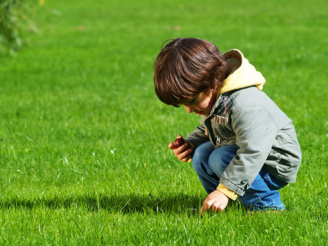 Dítě dřepí na trávě